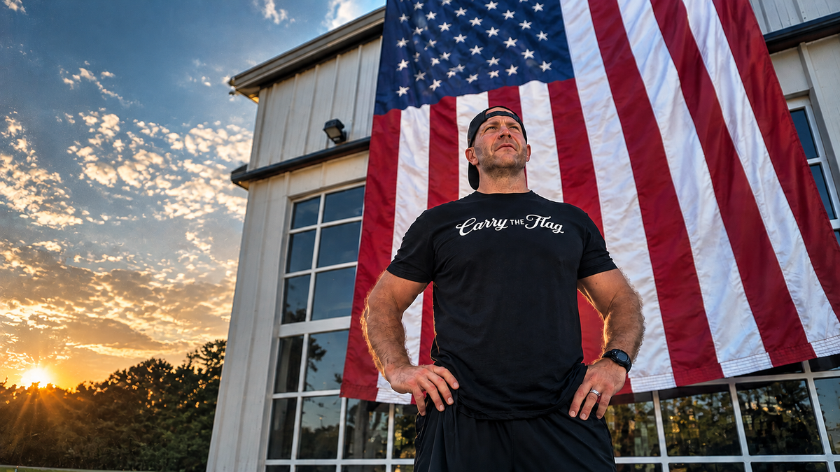 Man wearing a Carry The Flag shirt in front of an American flag